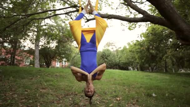 Aerial yoga practitioner stretches herself while suspended on hammock. — Stock Video