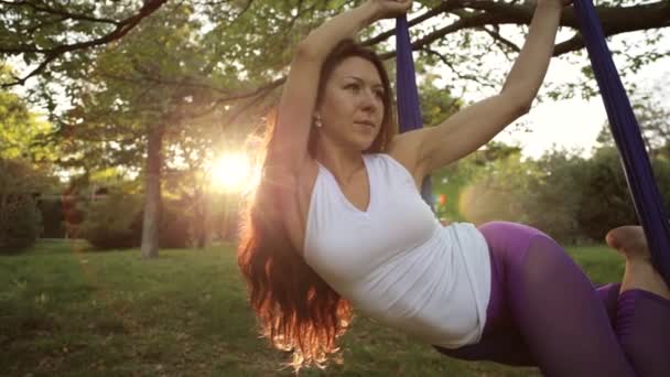 Praticante de ioga aérea se estende enquanto suspensa na rede . — Vídeo de Stock