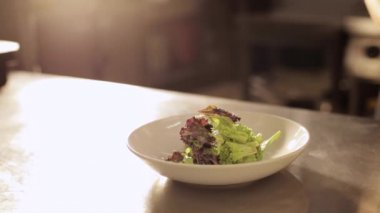 Şef eldiven ellerini koyar bir salata kaseden bir plaka üzerinde.