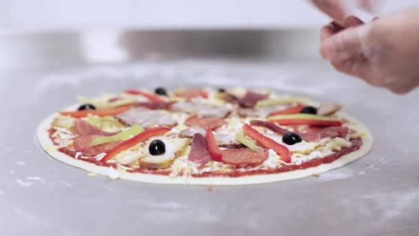 Szef kuchni dodając oliwki na pizzę w commercial kuchnia. — Wideo stockowe