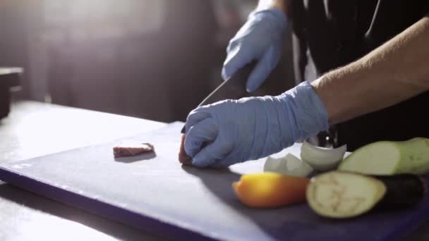 Handen van chef-kok snijden vers rauw vlees op een bord van de keuken in commerciële keuken — Stockvideo