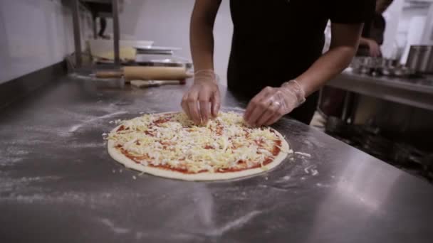 Chef poniendo queso encima de su base de pizza . — Vídeo de stock