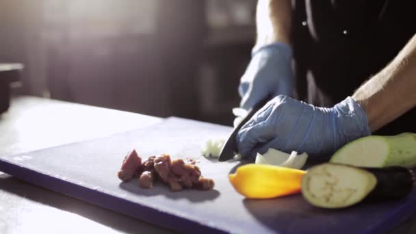 Руки шеф-повара в перчатках режут лук на коммерческой кухне — стоковое видео