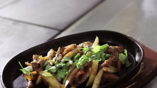 Tiro de verduras fritas con carne en sartén caliente sobre soporte de madera — Vídeos de Stock