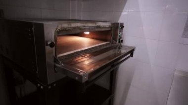 Ticari mutfak fırında içine çiğ pizza Chef koyar.