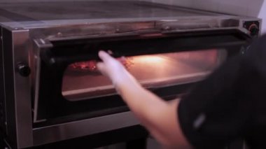 Ticari mutfak fırında içine çiğ pizza Chef koyar.