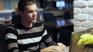 Kafede dizüstü ve içecek kahve üzerinde çalışan yakışıklı adam