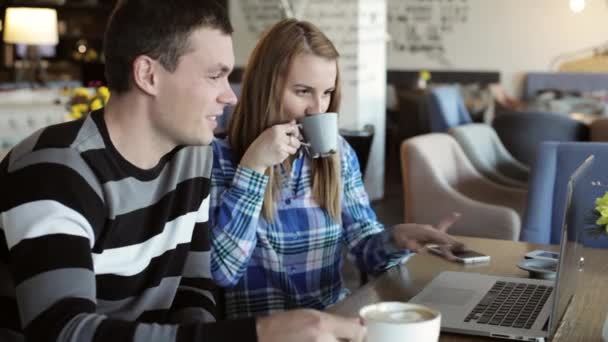 Jongen en meisje in café. Mensen gebruiken laptop en smartphones, praten en drinken koffie. — Stockvideo