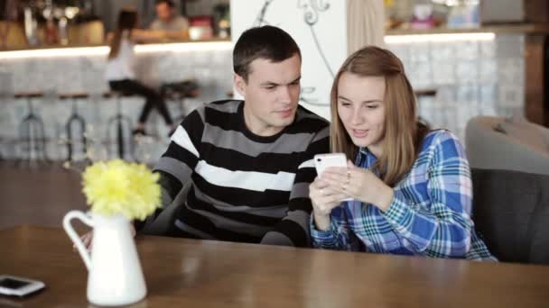 Femme et homme assis dans le café parler et regarder le téléphone dans la main — Video