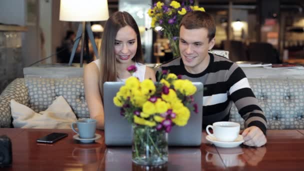 Unga kaukasiska par med modern laptop i café — Stockvideo