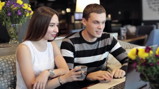 Jonge Kaukasische paar met moderne laptop in café — Stockvideo