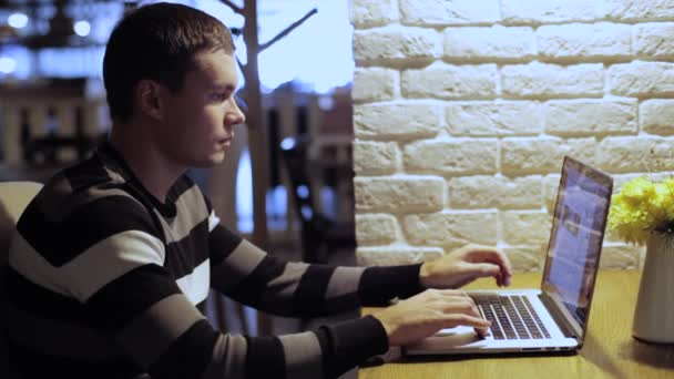 Knappe man aan het werk op laptop en drinken koffie in het café — Stockvideo