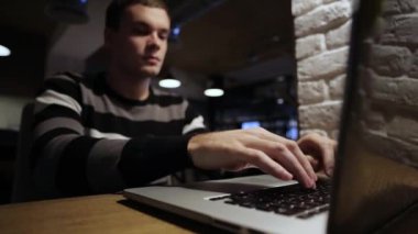 Kafede dizüstü ve içecek kahve üzerinde çalışan yakışıklı adam