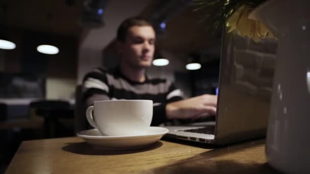 英俊的男人在笔记本电脑和喝咖啡在咖啡厅工作 — 图库视频影像