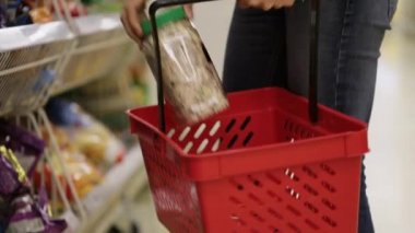Alışveriş sepeti süpermarkette kırmızı mal kadın koyar