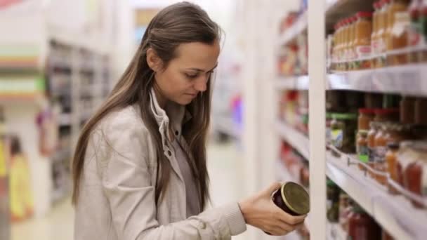 Молода жінка вибирає соус у банці в торговому центрі . — стокове відео