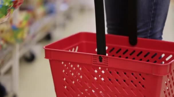 Mujer pone mercancías en la cesta roja de la compra en el supermercado — Vídeos de Stock