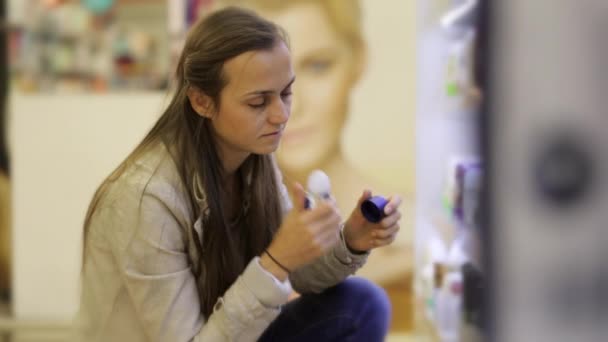 Junge kaukasische Frau wählt Deo in Schönheitsabteilung des Einkaufszentrums. — Stockvideo