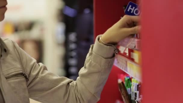 Jeune femme faisant du shopping dans le magasin de cosmétiques pour femmes, sélectionne certains produits . — Video