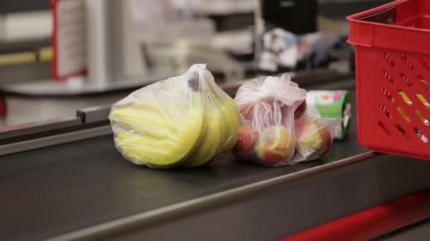 Los clientes ponen frutas de la cesta de la compra en el mostrador del cajero en el hipermercado — Vídeo de stock