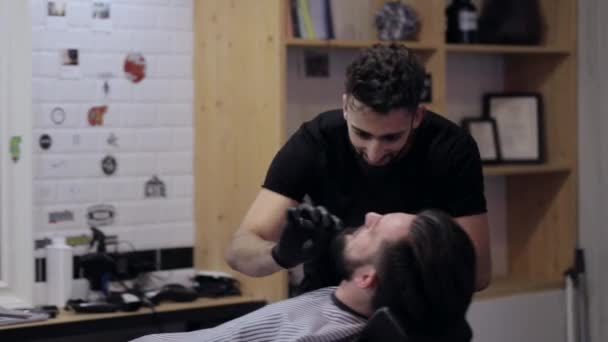 Friseur tanzt, singt und schneidet Bart mit Rasiermesser beim Friseur. — Stockvideo