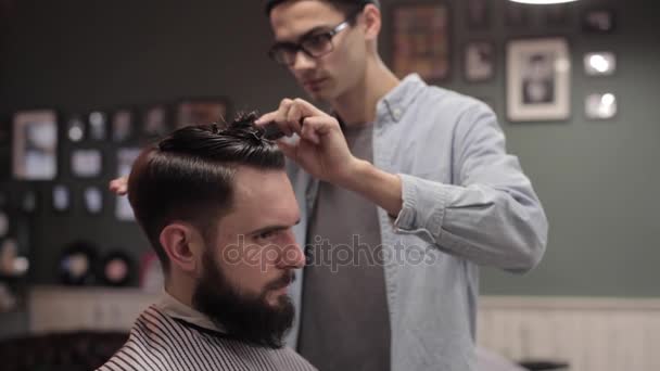 Парикмахер стрижет волосы клиента ножницами — стоковое видео