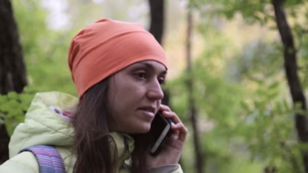 Woman in warm wear talking on cellphone in the autumnal forest. — Stock Video