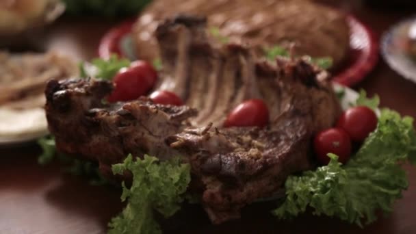 Banquet table with big piece of grilled meat with tomatoes and lettuce — Stock Video