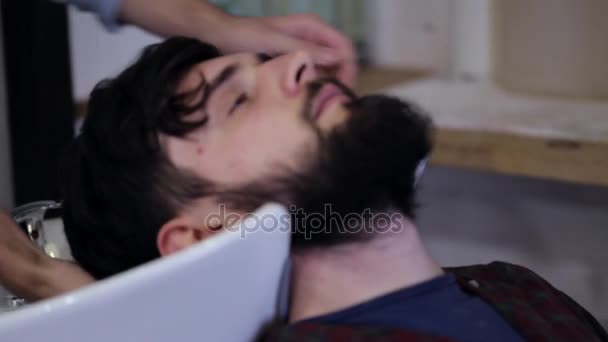 Чоловік перукар миє чоловіче клієнтське волосся в перукарні, крупним планом — стокове відео