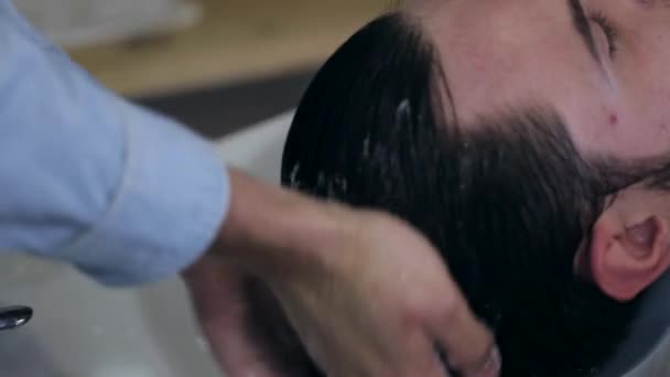 Uomo barbiere lavaggio capelli maschili cliente in un barbiere, primo piano — Video Stock