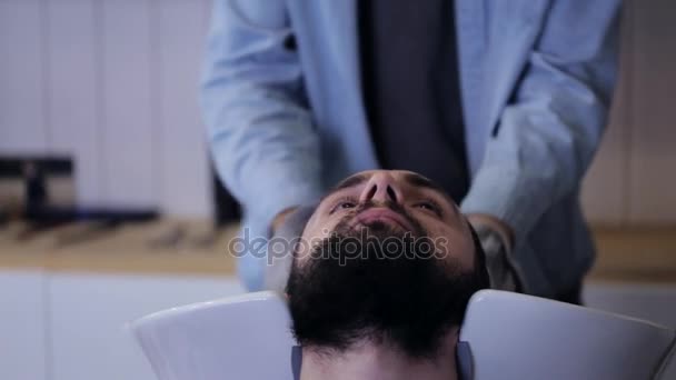 Toallitas de peluquero macho lavan el cabello de un guapo cliente masculino con una toalla en la barbería — Vídeo de stock