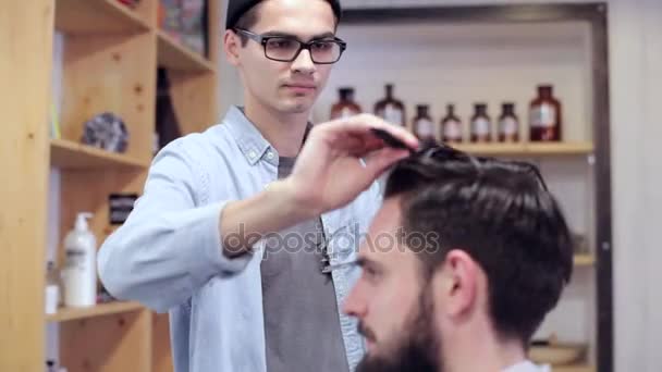 Парикмахер расчесывает волосы клиента перед стрижкой в парикмахерской — стоковое видео