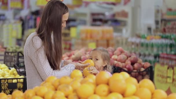 Anya és a baba lánya szupermarketben vásárol gyümölcsök és zöldségek — Stock videók