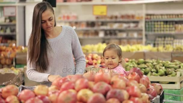 Moeder en baby dochter in de supermarkt kopen groenten en fruit — Stockvideo