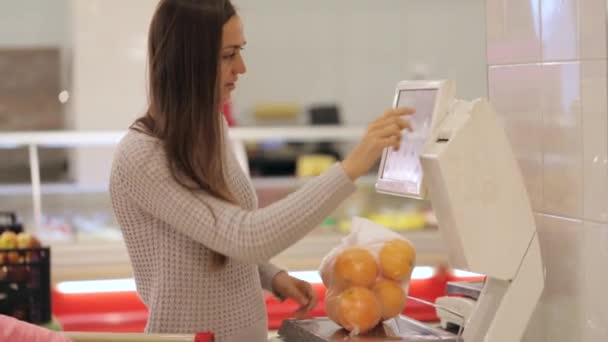 年轻的母亲的小女儿加权蔬菜和水果在超市 — 图库视频影像
