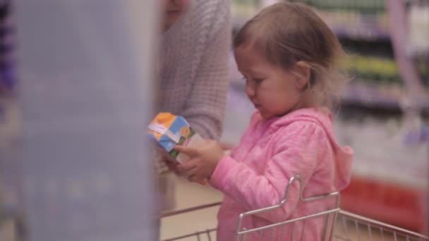 Frau mit Tochter pflückt frische Milchprodukte im Kühlfach — Stockvideo