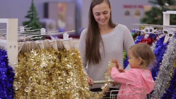 Jovem mãe atraente com compras de menina decorar para a árvore de Natal . — Vídeo de Stock