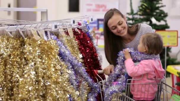 Ibu muda yang menarik dengan gadis kecil membeli hiasan untuk Natal-pohon . — Stok Video