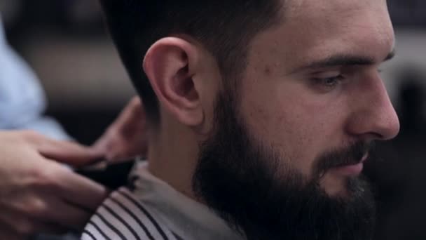 Joven peluquero guapo haciendo corte de pelo de hombre barbudo atractivo en la barbería — Vídeos de Stock