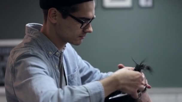 Male barber with a male client at barbershop. Barber cutting hair with scissors. — Stock Video