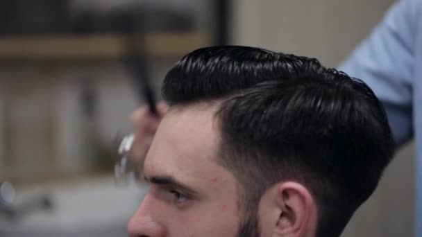 Jovem barbudo na barbearia. Barbeiro pentear o cabelo do cliente . — Vídeo de Stock