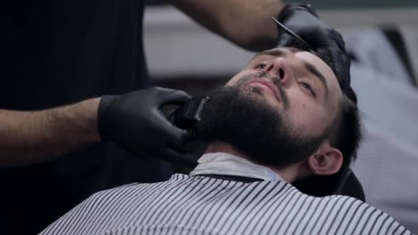 Barba de corte de peluquero macho con afeitadora eléctrica en una peluquería . — Vídeos de Stock