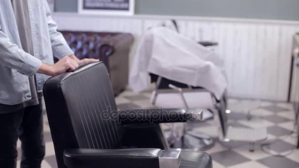 Ein Mann setzt sich auf einen Friseurstuhl in einem Friseursalon — Stockvideo