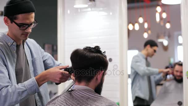 Un hombre guapo con barba en la barbería. Peluquero trabajando con afeitadora eléctrica . — Vídeos de Stock