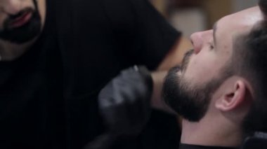 Erkek bir istemci kesme sakal tıraş kullanarak bir Kuaför Close-Up.