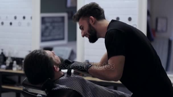 Barbeiro barba a barba do cliente na barbearia — Vídeo de Stock