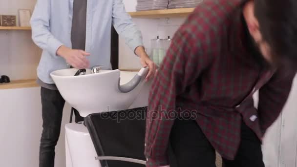 木こりが理髪店で洗浄ヘッドのための椅子に座る. — ストック動画