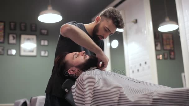 Holič, příprava jeho klient pro holení v retro kadeřnictví. — Stock video