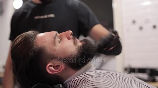 Barber peinando la barba del cliente en una peluquería . — Vídeos de Stock