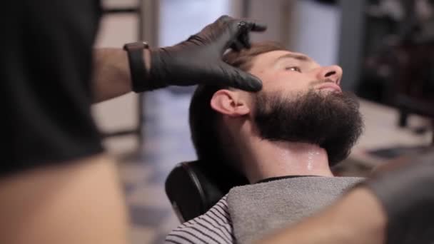 Peluquero preparando a su cliente para un afeitado en una peluquería vintage . — Vídeo de stock